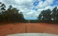 Open road of red soil viewed from the driver's seat. Country Aboriginal art