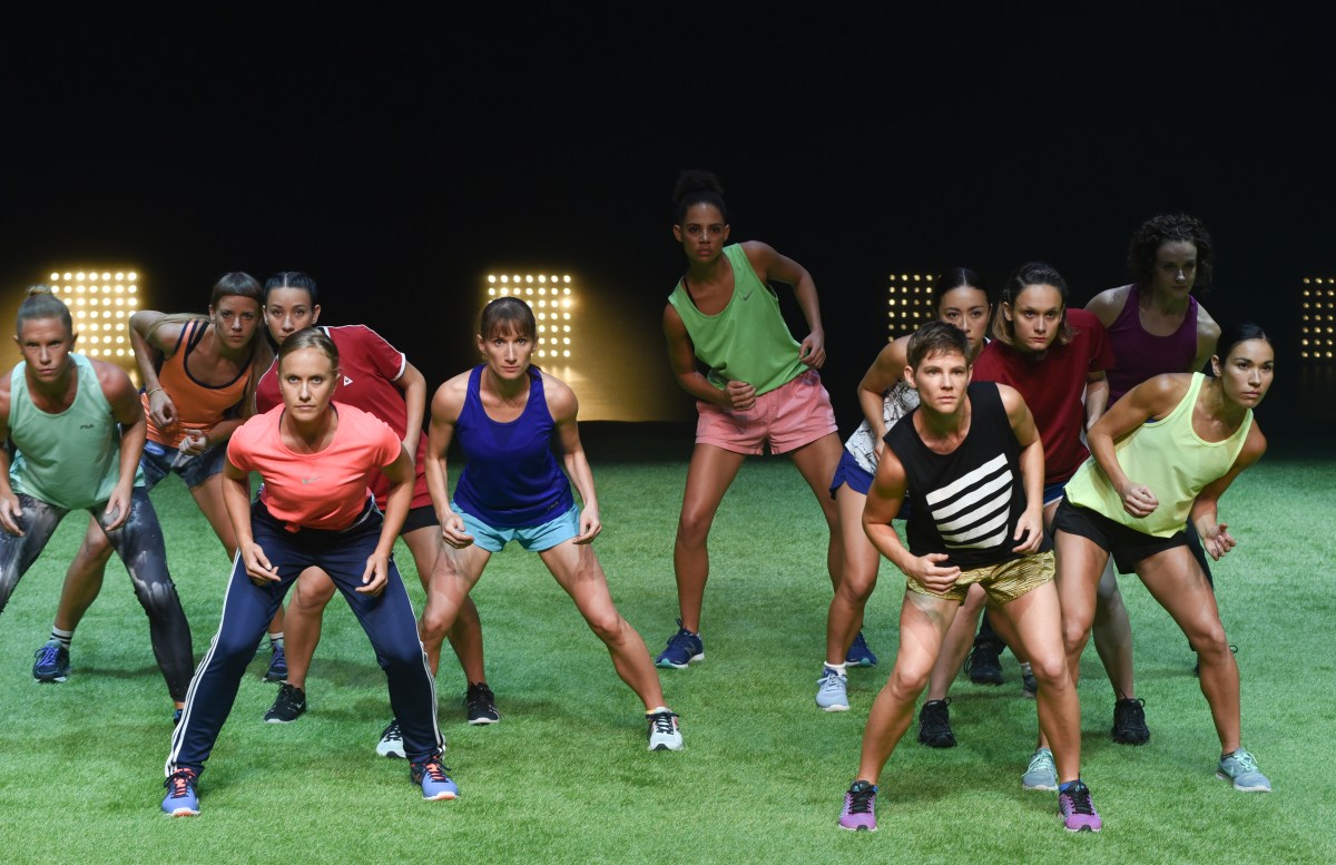 performers facing the audience on stage in a sporting formation as if on a soccer field