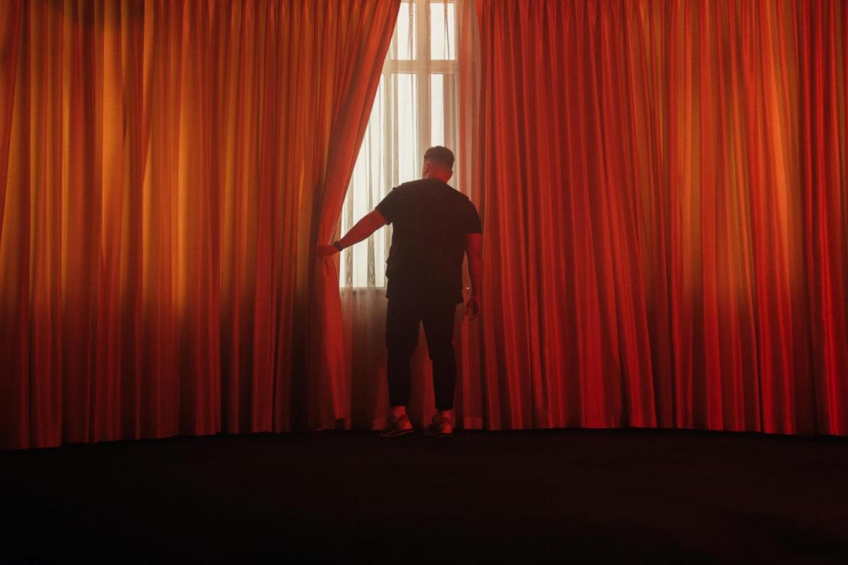 a man pulling back a big red curtain