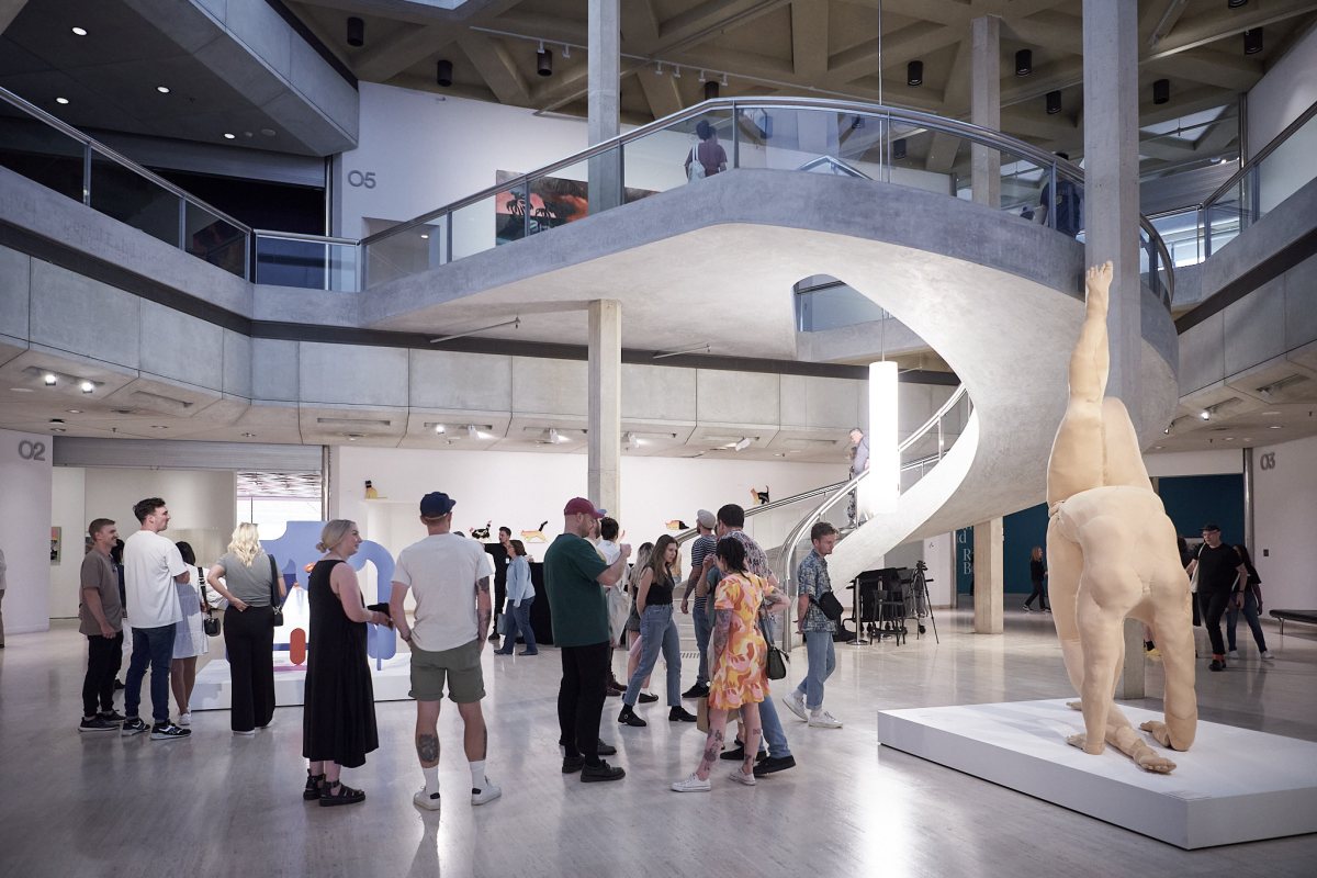 a huge gallery ground floor space with visitors looking at artworks