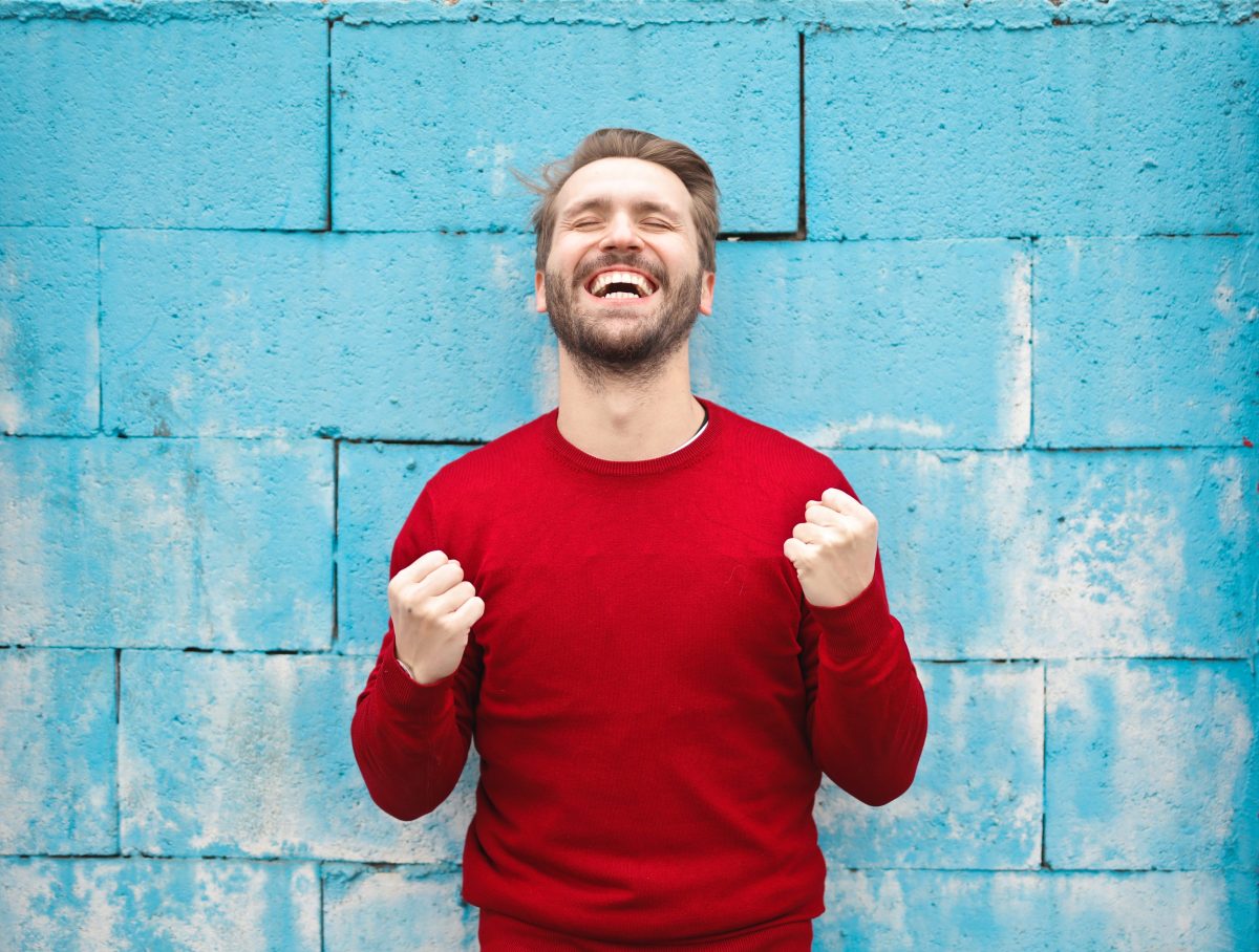 a man in front of a blue wall celebrating a win.