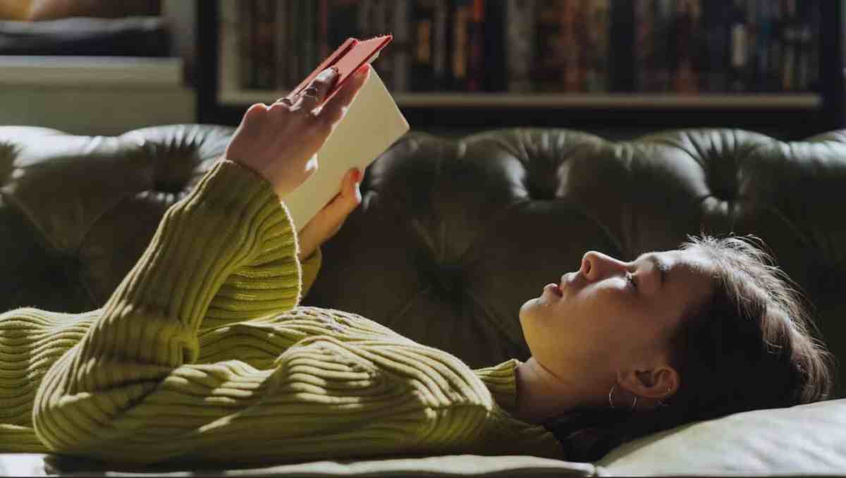 girl reading book on lounge