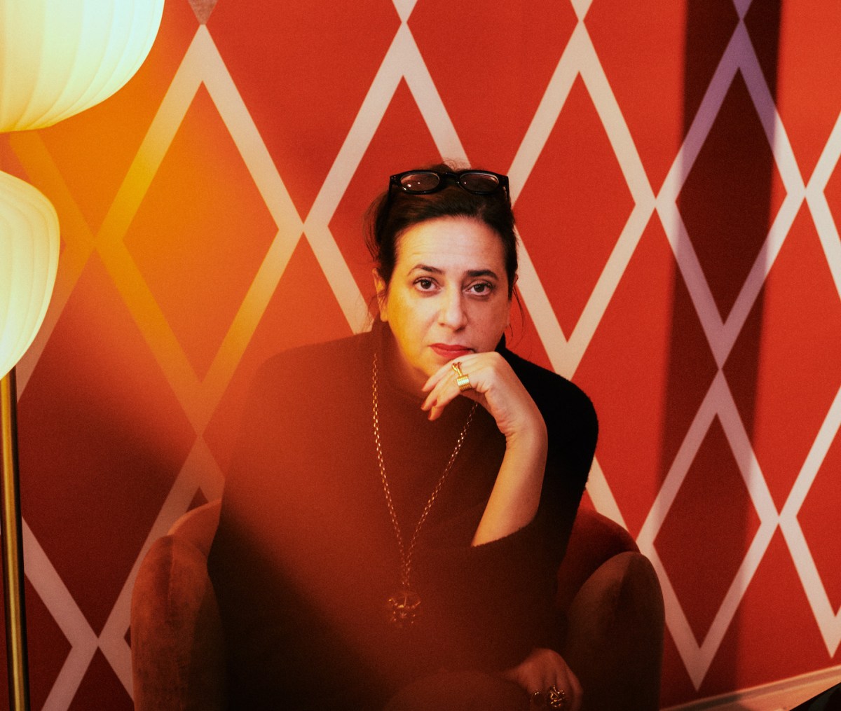 Designer India Mahdavi photographed against patterned red wallpaper