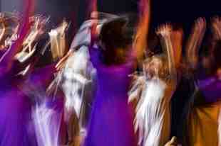 A blurred image of a group of dancers, giving the impression of rapid collective movement.