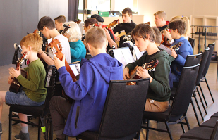 group of children learning how to play guitar