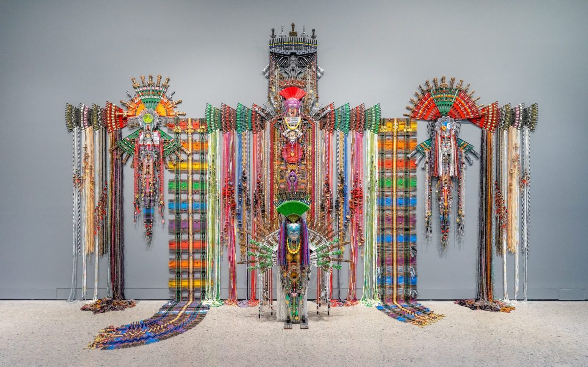 Taipei Dangdai, Evoke sector. Anne Samat, ‘Never Walk In Anyone's Shadow,’ 2023, Rattan sticks, kitchen and garden utensils, beads, ceramic, metal and plastic ornaments. Photo: Brian Holcombe. Image: Courtesy of the artist and MARC STRAUS. A large colourful installation that appears like a folk monument against a grey background.