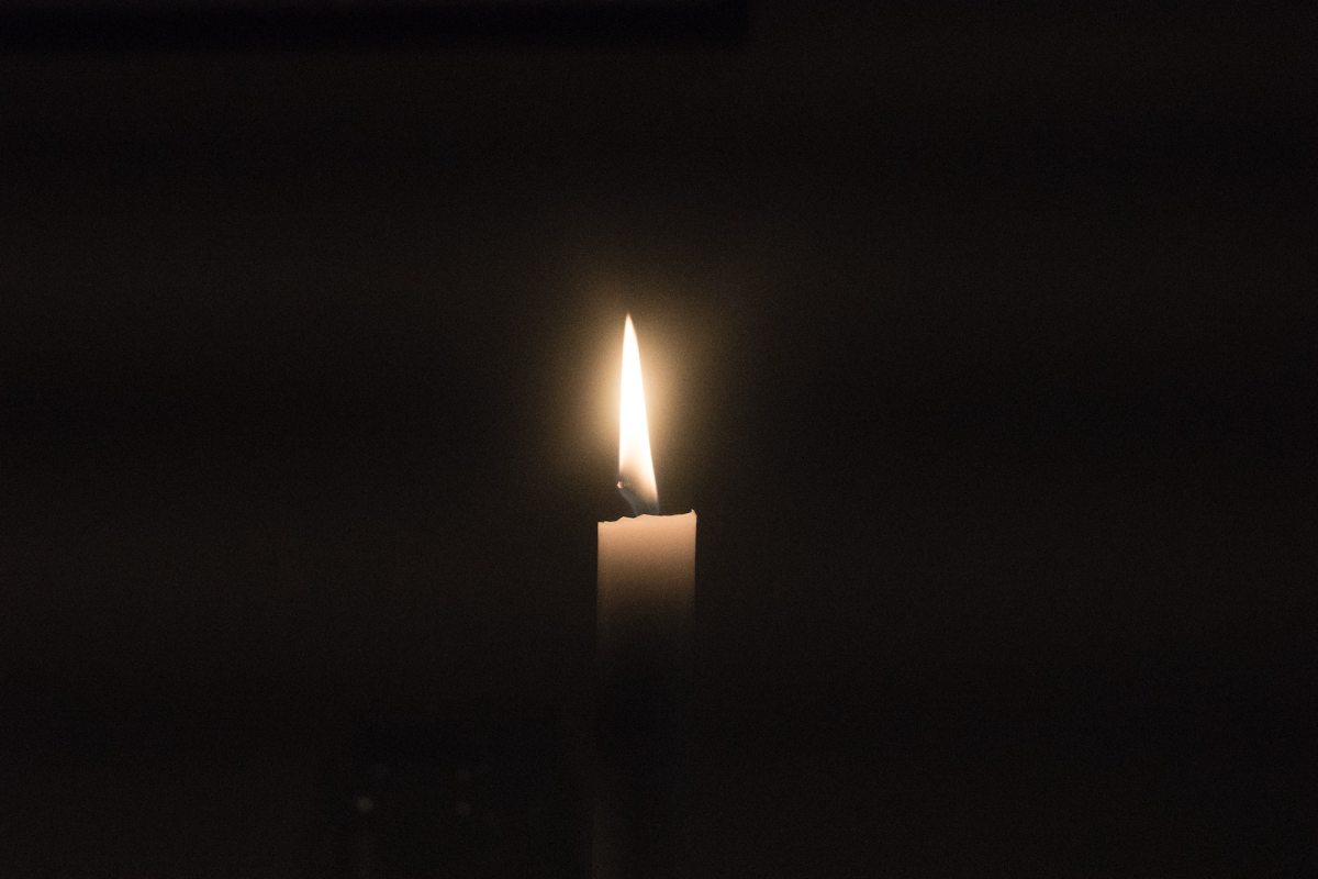 A lit candle against a black backdrop. Vale