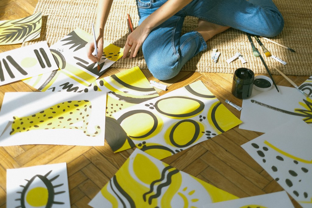 sitting on floor doing yellow and black abstract paintings. Mental Health