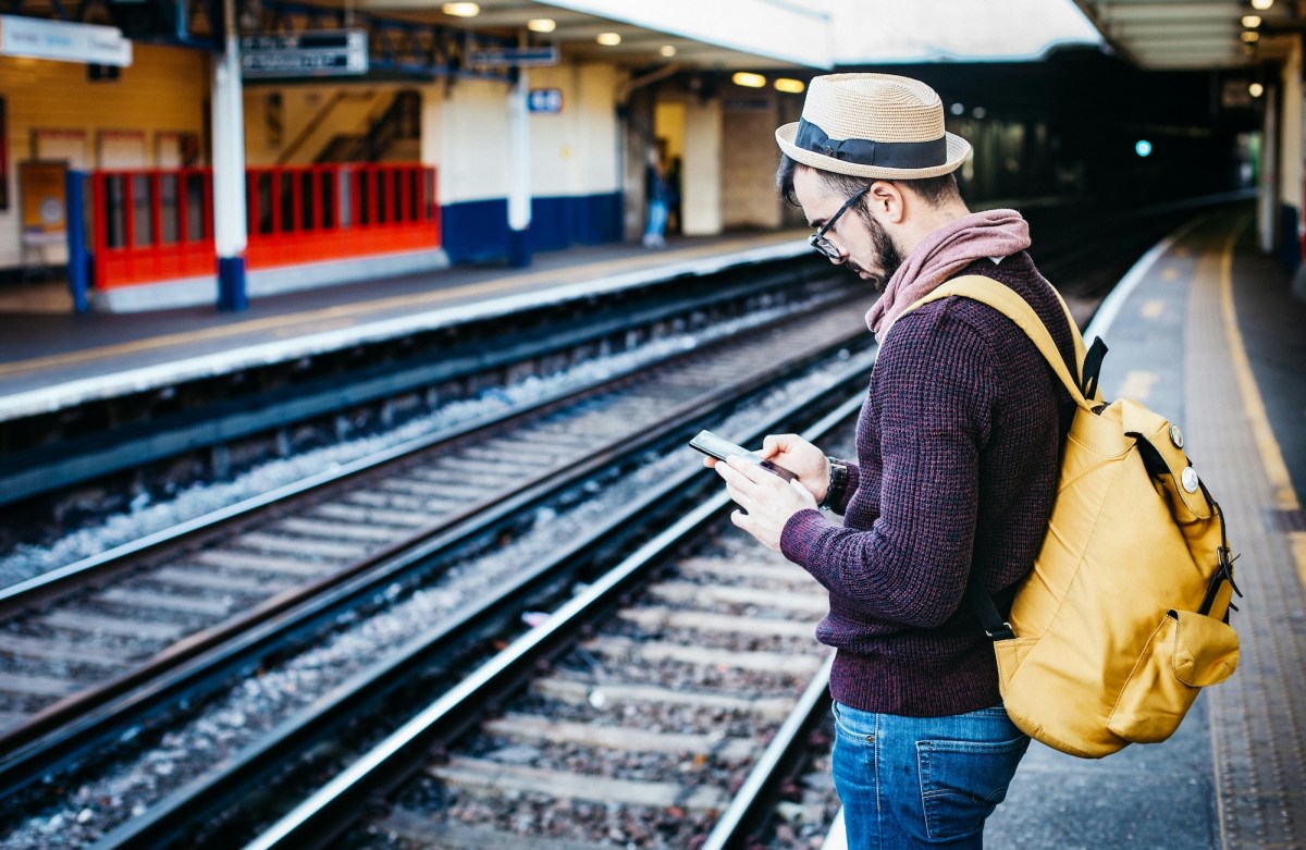 man reading news while waiting for train. Arts news