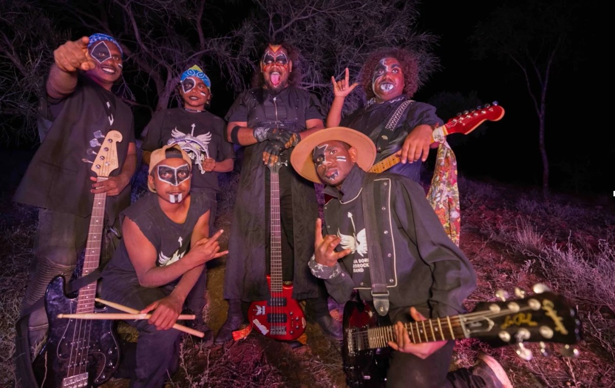 A group of Aboriginal musicians pose for the camera. They are wearing KISS like face makeup.