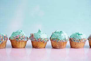 launch your book. Image is a row of six cup cakes with turquoise icing and sprinkles on the top.