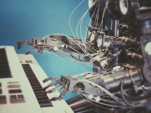 A robot uses its mechanical fingers to play the keyboard.