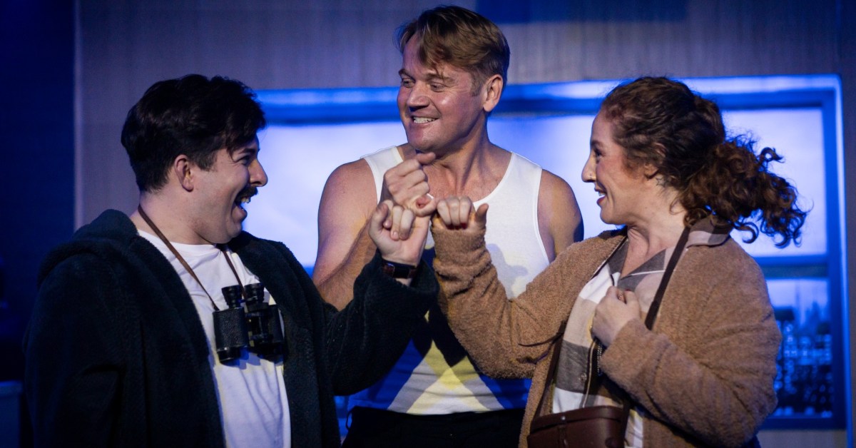 Two male actors and one female actor clasp hands excitedly.