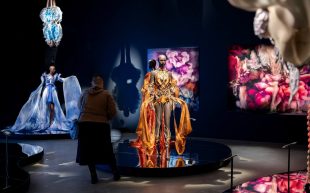 'Iris van Herpen: Sculpting the Senses' at Queensland Gallery of Modern Art. Photo: Supplied. A darkened room with mannequins displaying vibrant garments with floral patterns.
