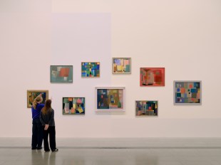 Two people looking at colourful abstract paintings in gallery. Crowley Balson.