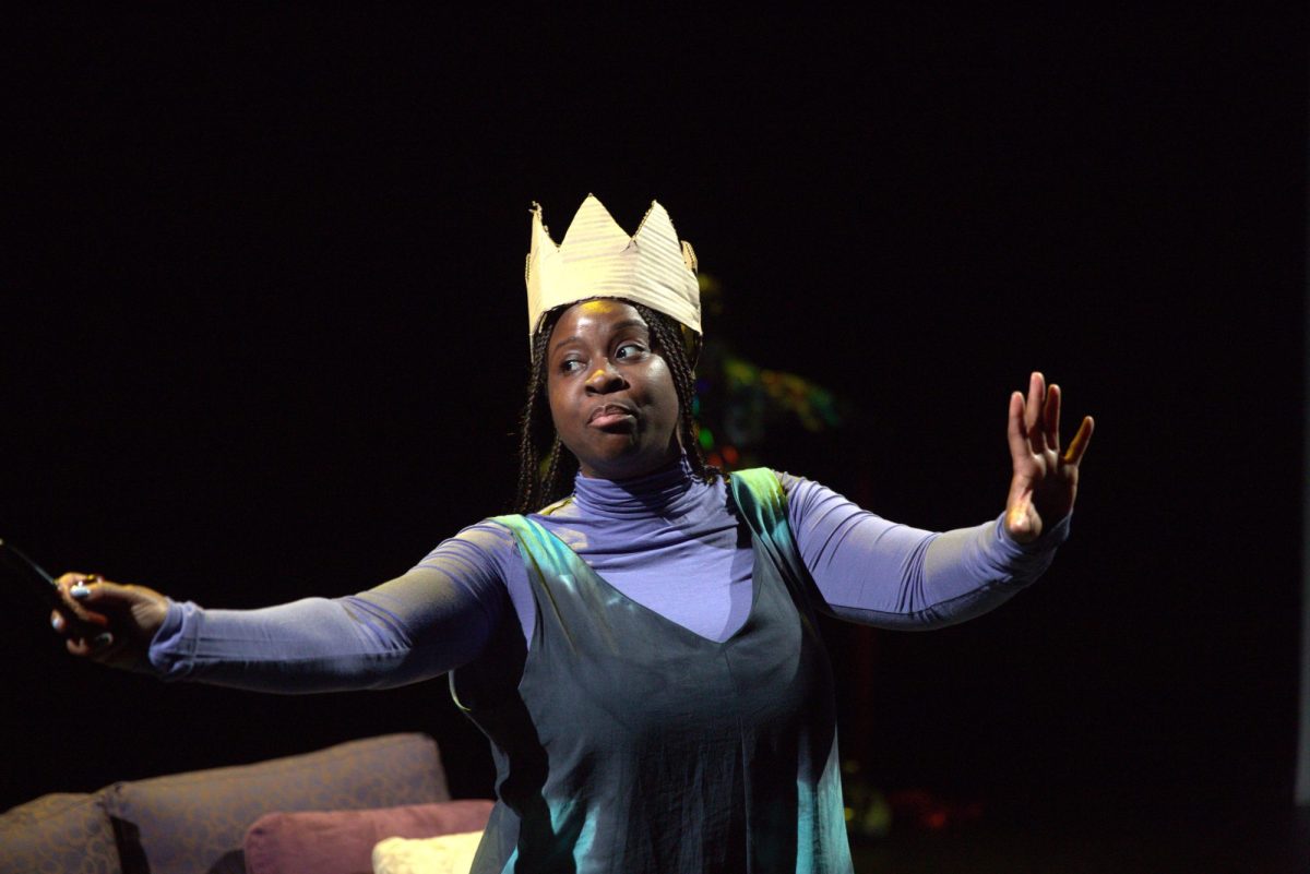 A woman wearing a cardboard crown. She has a black top over a light blue skivvy. La Belle Epoque.