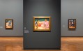 Gallery with grey walls displaying bright tropical paintings by Gauguin.