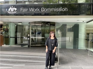 Woman dressed in black with white frame glasses standing in front of Fair Work Commission building. NAVA