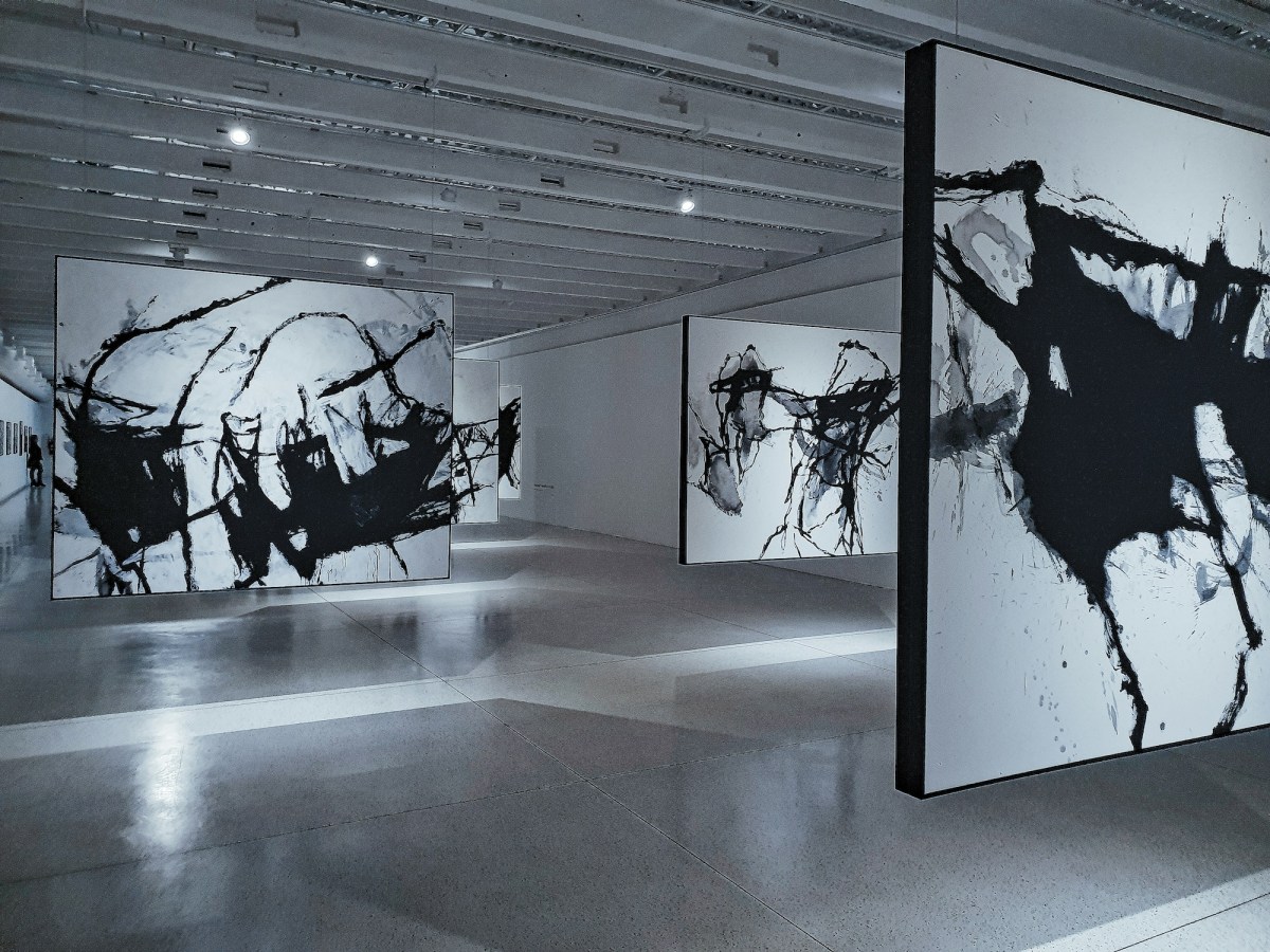 Gallery with black and white abstract paintings hovering in the space. Exhibition.