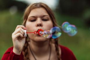 woman in red sweater blowing bubbles. Arts news.