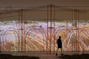 Gallery view of man walking in an immersive exhibition with video projection and metal sculpture. Unsettling Queenstown.