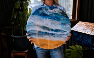 Make your own resin lazy susan at 2024 Margaret River Region Open Studios. Photo of a person holding a resin circular board resembling ocean waves.