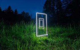 Bronte Cormican Jones, ‘Lightlines’, 2023, a work commissioned by Canberra Art Biennial. Three neon light installations that appear like doorframes displayed in a grassy environment at night.