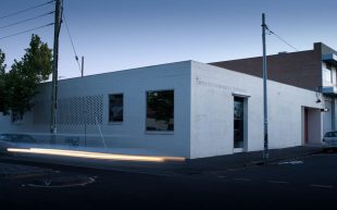 The exterior of CCP’s Fitzroy home. A rectangular white brick building at dusk.