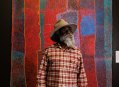 Aboriginal artist with abstract painting in red colours. NATSIAA