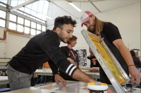 Two male art students in studio making silk screen prints. NAS.