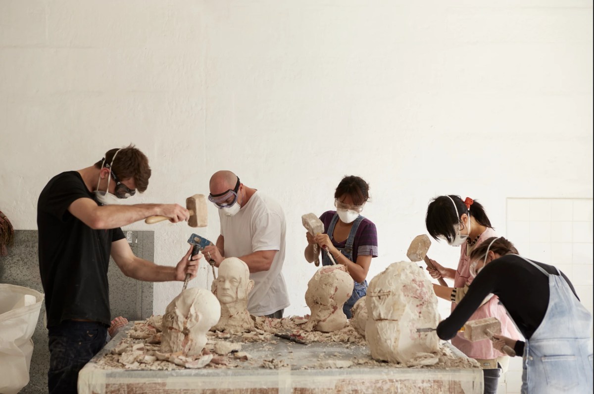 Group of art students making sculptures of stone and plaster heads. NAS.