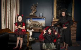 'Victorian vampires' wins popular vote at Australian Life photography competition, taken by Chrissie Hall of herself and her two daughters dressed up. The photo sets up the ambiance of a Victorian era home with animal taxidermy, vintage leather sofas and low lighting. The three are depicted wearing black and red gowns and sharp vampire teeth.