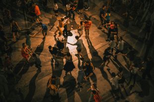 An overhead photograph of an adult dance class, showing groups of couples circling around the floor.