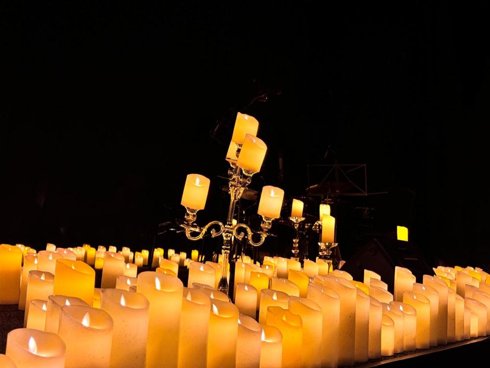 A sea of battery-operated candles on the stage as well as a candelabra with candles on them.