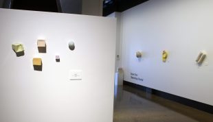 A number of small ceramic artwork are attached to two white walls.