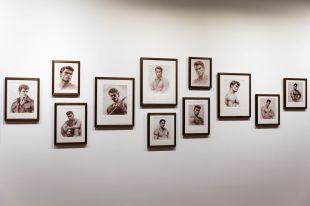 Installation view of Clinton Hayden's 'mudyigalang-gu ngurambang-gu' at Latrobe Regional Gallery, showing a number of black and white portraits of Aboriginal men, in a style referencing the artist Tom of Finland. The art works are hung in black frames on a white wall.