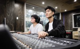 UTS Creative Arts. Two young men of Asian appearance sit at a mixing desk in a production studio.