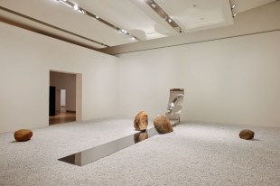 Gallery setting with white pebble floor and mirror stip with stone boulders. Lee Ufan.