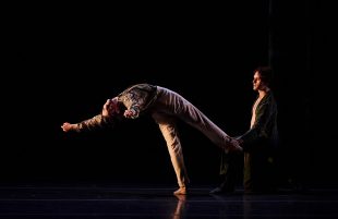 Benjamin Garrett as Bosie and Callum Linnane as Oscar Wilde in The Australian Ballet's 'Oscar', choreographed by Christopher Wheeldon. A moody photo depicting the sexual relationship between Oscar and Bosie through dance, with Bodie's foot hooked behind Oscar's leg as he leans away.