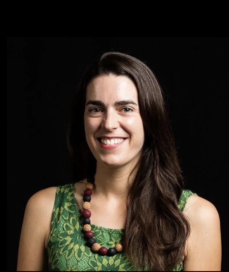 Young woman with long dark hair and green sleeveless top. Curator Caityln Eyre