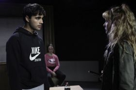 two young ATYP actors, one male, one female, pictured facing each other onstage engaged in serious conversation.