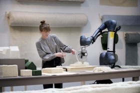 Woman with robotic machine creating cream wool sculpture. NGV commission