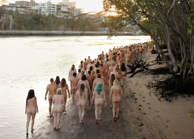 Group of naked people walking along river edge. Spencer Tunick