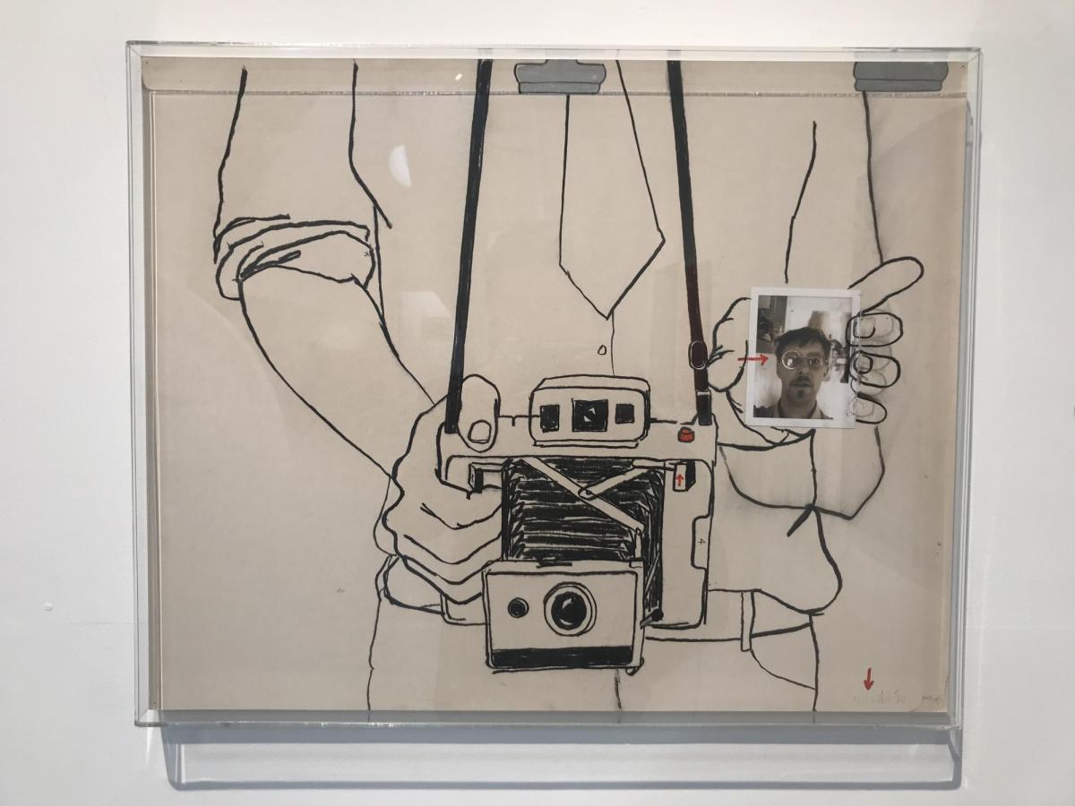 An illustration line drawing of a man's torso with a Polaroid around his neck. He is carrying a photo of his face. Tony Woods.