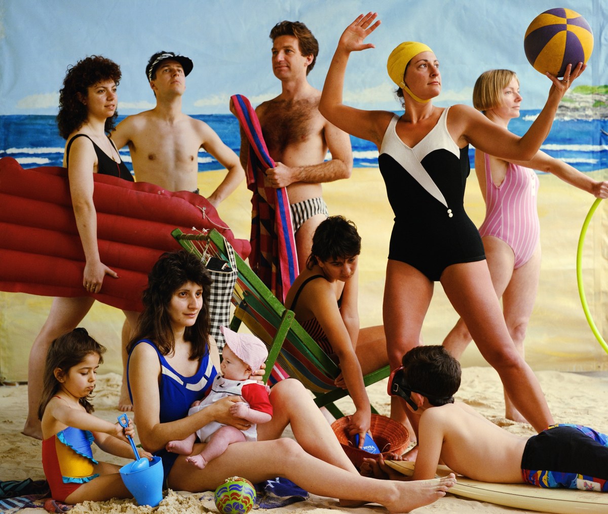 A tableau of people on a beach, holding typical poses - carrying an airbed, playing with a beach ball, children with buckets and spades. Some are archetypal Anglo Aussies, some are darker haired, non Anglo looking.