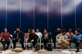 Diverse group of people seated and chatting against dark blue background. Audience.