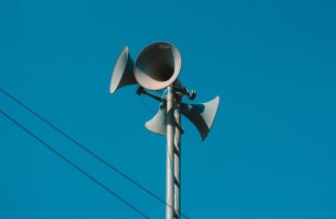 Old fashion speakers on top of pole against clear blue sky. Arts news.