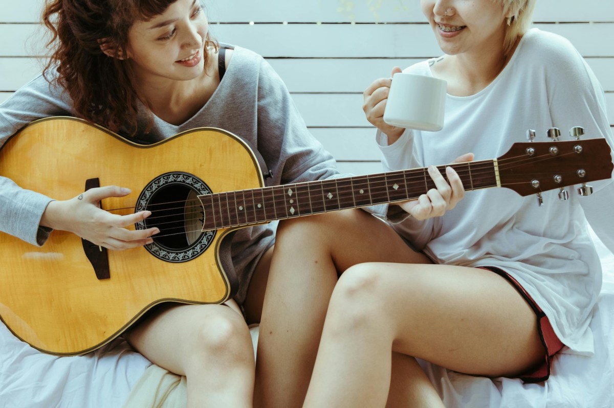 two young women playing a guitar.