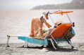 Elderly woman on sun lounge at beach reading. Art books