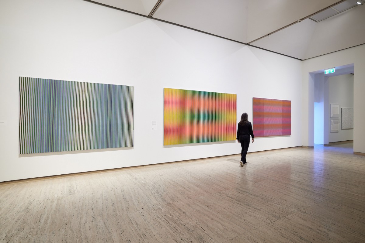 person in black looking at optical abstract paintings in gallery setting. Lesley Dumbrell